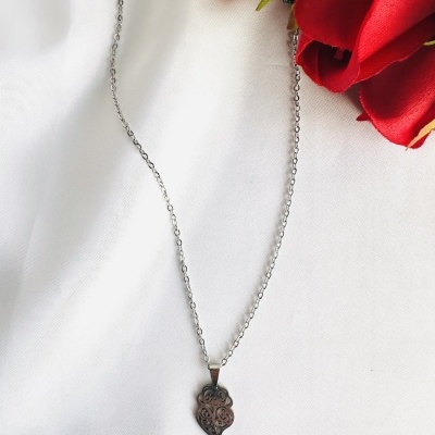 Colar com pendente de coração prateado e flores vermelhas ao lado