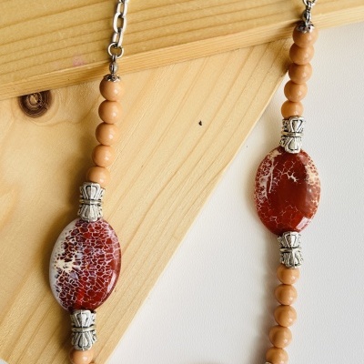 Colar com contas bege e ovais marmoreadas vermelhas com detalhes metálicos prateados