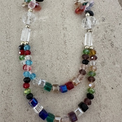 Colar com contas de vidro coloridas e transparentes sobre fundo cinzento rugoso