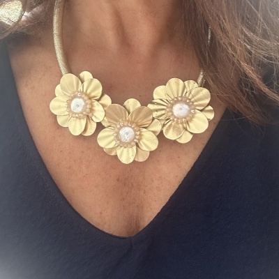 Colar de flores douradas com pérolas e cordão dourado sobre vestido azul