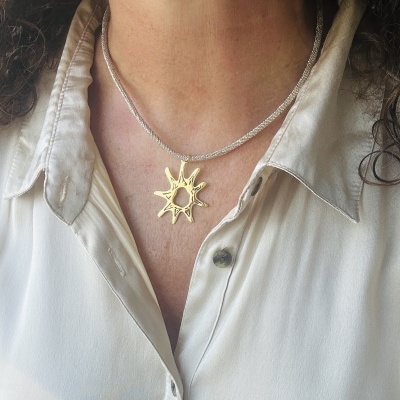 Colar prateado com pendente dourado em forma de sol