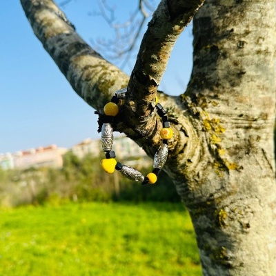 pulseira colorida pendurada num ramo de árvore com fundo de campo verde