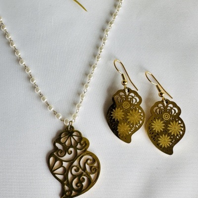 Colar com corrente de pérolas brancas e pendente dourado com desenho vazado e brincos dourados com padrão floral