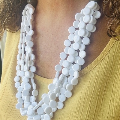 Colar de contas brancas redondas usado com blusa amarela