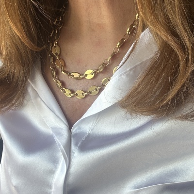 Colar dourado com elos elípticos sobre blusa branca acetinada