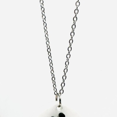 Colar prateado com pendente redondo branco e silhueta preta de duas pessoas abraçadas