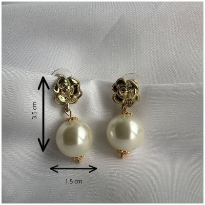 Brincos dourados com pérolas pendentes sobre tecido branco