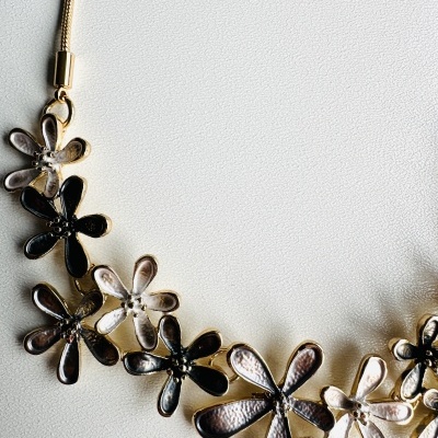 Colar flores metálicas dourado e prateado sobre fundo branco