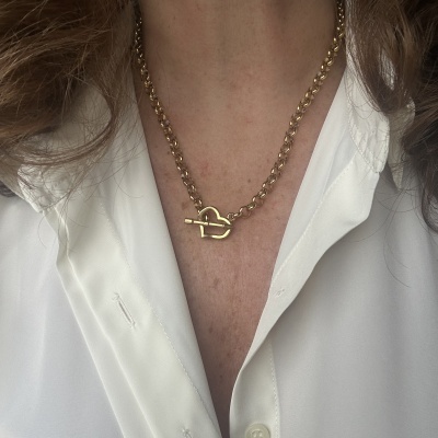 Colar dourado com fecho em forma de coração usado com camisa branca