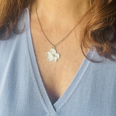 Colar com pendente flor branca em pescoço com camisola azul clara