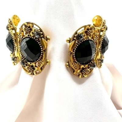 Brincos vintage dourados com pedras pretas sobre tecido branco e bege