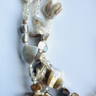 Colar de conchas iridescentes e contas transparentes sobre fundo branco