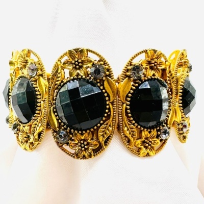 Pulseira dourada com pedras pretas facetadas grandes e detalhes florais