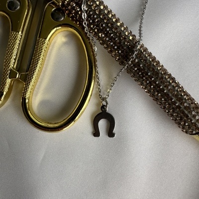 Colar com pendente de ferradura e acessórios dourados sobre tecido branco