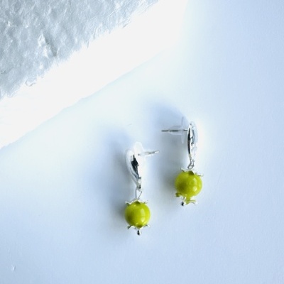 Brincos prata com pedra verde sobre fundo azul claro