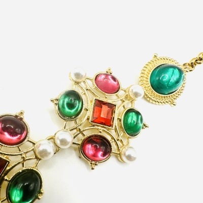 Colar dourado com pedras coloridas e pérolas sobre fundo branco