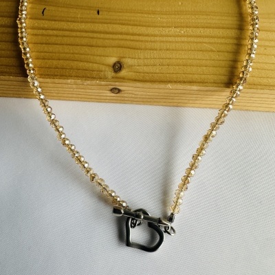 Colar de contas douradas com fecho prateado em forma de coração.