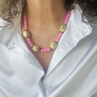 Colar com contas cor-de-rosa e douradas em pescoço com camisa branca