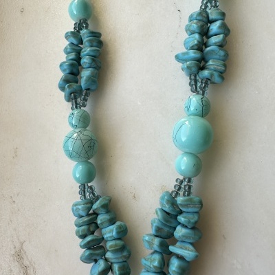 Colar azul turquesa com várias contas de diferentes formatos em fundo branco