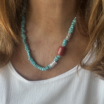 colar azul turquesa com contas prateadas e vermelhas sobre camisa branca