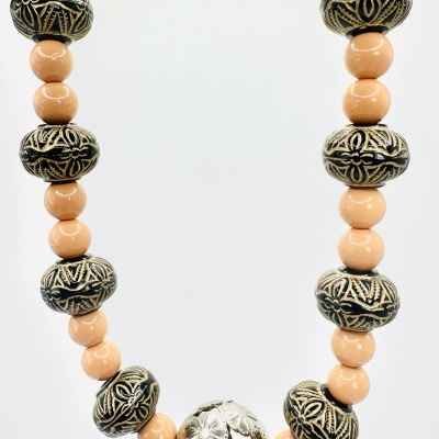 Colar com contas pretas e bege alternadas e conta prateada central com relevos florais
