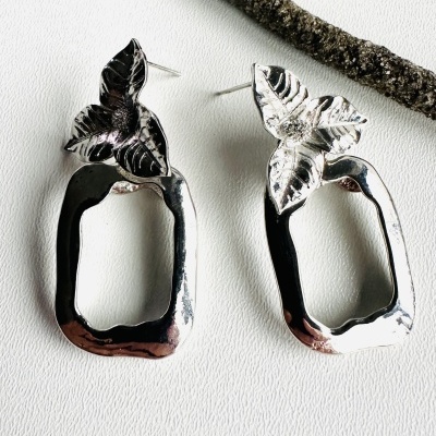 Brincos prateados com folhas e formas geométricas irregulares