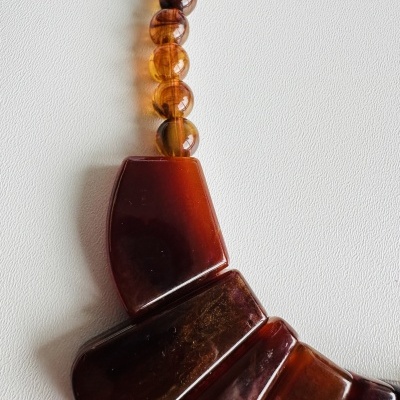 Colar com contas âmbar e pendentes castanho avermelhado sobre fundo branco