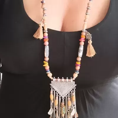 Colar longo com contas coloridas e franjas bege sobre blusa preta