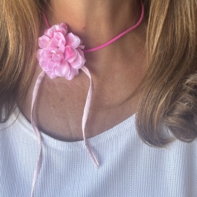 Colar rosa com flor de tecido e cordão fino em pescoço