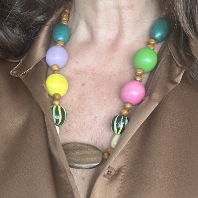 Colar colorido com contas grandes usado sobre camisa castanha satinada