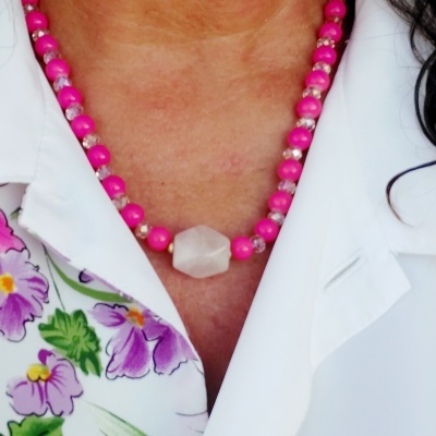 Colar de contas cor-de-rosa e conta central branca numa blusa floral e blazer branco