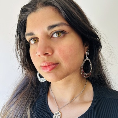 Colar prateado com pendente oval e brincos de argola prateados usados por mulher