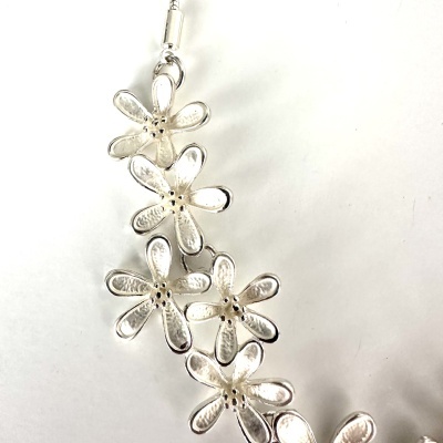 Colar com flores metálicas prateadas em fundo branco