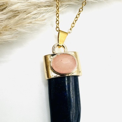 Colar dourado com pendente em forma de dente preto e topo com pedra rosa