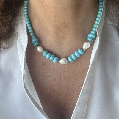 Colar com contas azuis e pérolas numa pessoa com camisa branca