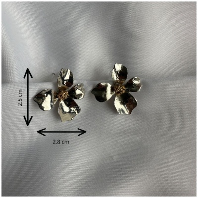 Brincos flor metálicos dourados sobre pano branco