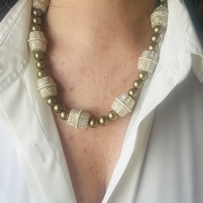 Colar com contas brancas gravadas e contas douradas usado com camisa branca