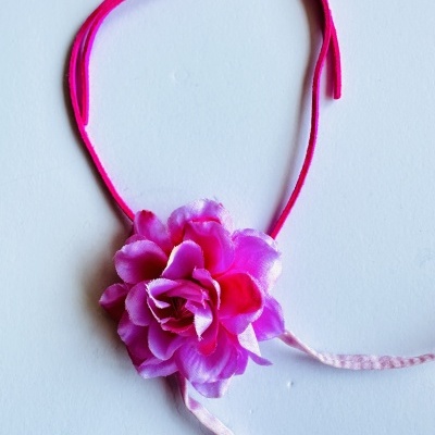 Colar com flor artificial rosa e lilás sobre fundo branco