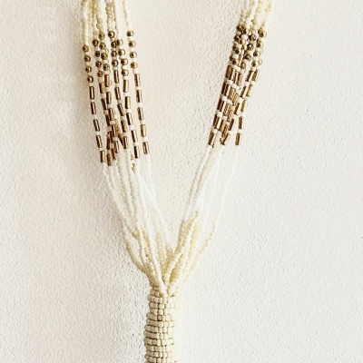 Colar de contas brancas e douradas com franjas e nó central pendurado