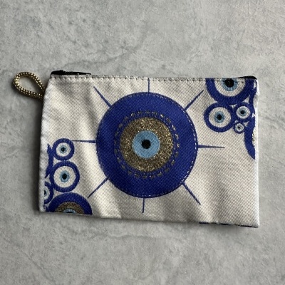 Carteira pequena branca com padrão olhos turcos em azul e dourado.