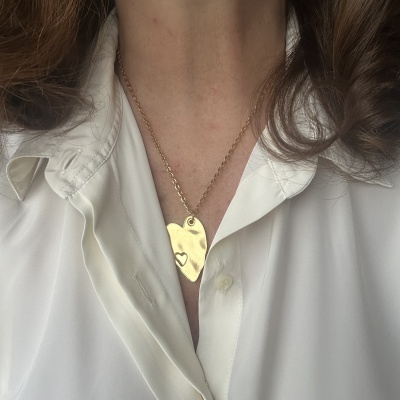 Colar dourado com pendente em forma de coração e pequeno recorte em forma de coração