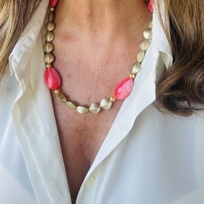 Colar com contas douradas e vermelhas usado com camisa branca
