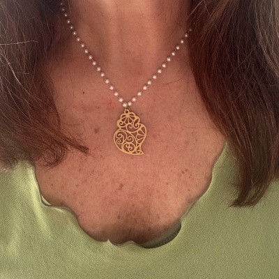 Colar de pérolas com pendente dourado com padrão arabesco