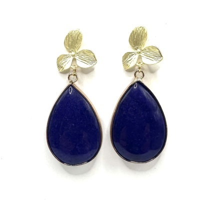 Brincos dourados com pendente azul gota sobre fundo branco.