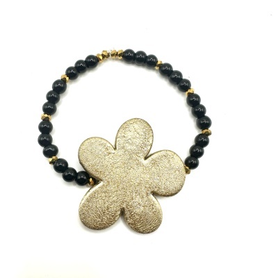 Pulseira preta com adorno dourado em forma de flor.