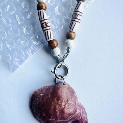 Colar com contas em tons castanho e branco, com pendente em forma de concha rosa escura
