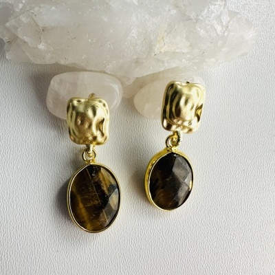 Brincos dourados com pedras castanhas sobre cristais transparentes