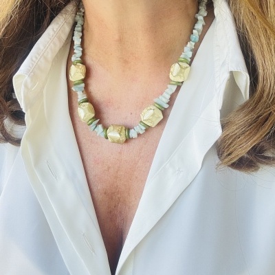 Colar de pedras douradas e azul-claro numa camisa branca.