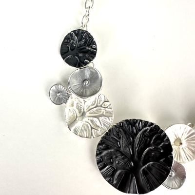 Colar com pendentes redondos preto e prateado textura natural sobre fundo branco