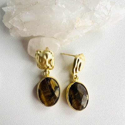 Brincos dourados com pedra castanha pendente sobre cristal branco